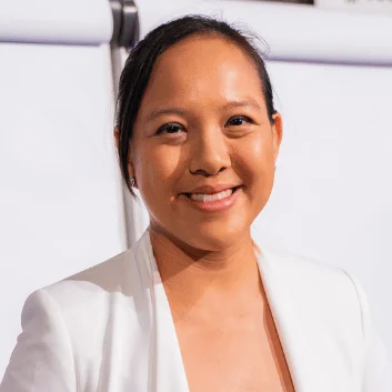 Patricia Lin, smiling, in a white blazer beside a flip chart
