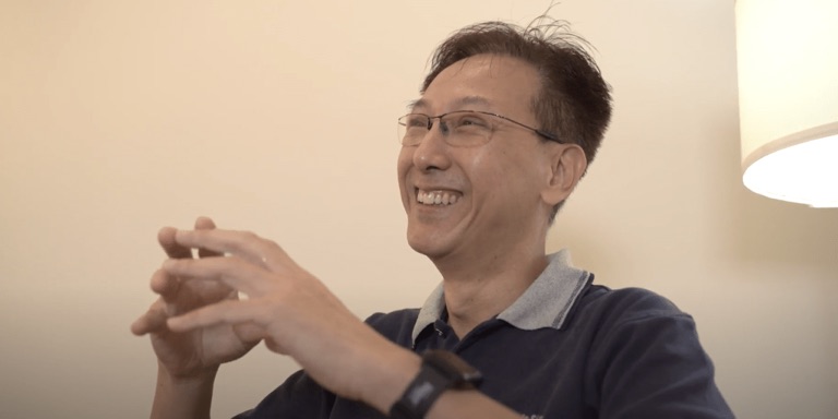 Lewis Tan smiling and talking with his hands during an interview